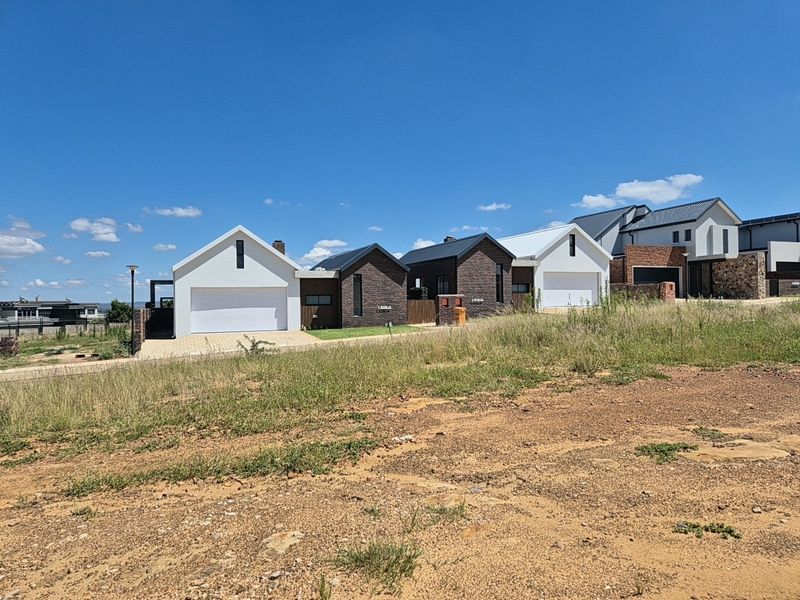 A view of modern residential homes with paved driveways and garage access, situated in a developing estate setting.