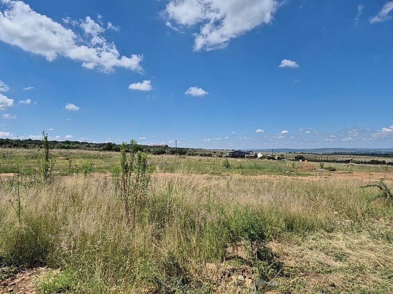 A wide-angle view of an expansive, undeveloped residential plot featuring natural grassland and distant horizon views.