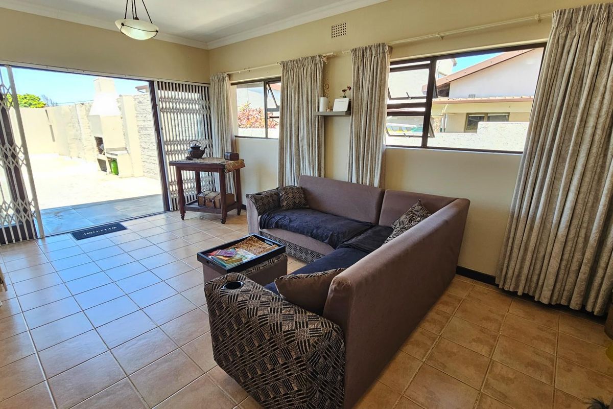 A bright living room featuring tiled flooring and large sliding doors that provide seamless access to an outdoor patio area.