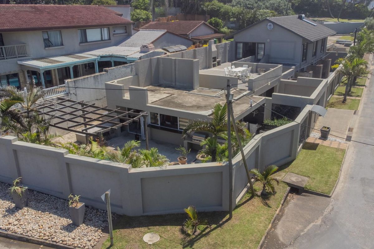 Aerial view of a residential property featuring a flat-roofed structure, enclosed courtyard, pergola, and perimeter boundary walls in a suburban setting.
