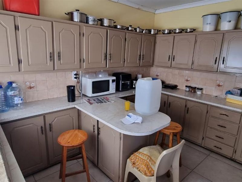 A functional kitchen featuring extensive built-in cabinetry, laminate countertops, and a tiled backsplash, offering a practical layout with ample storage space.