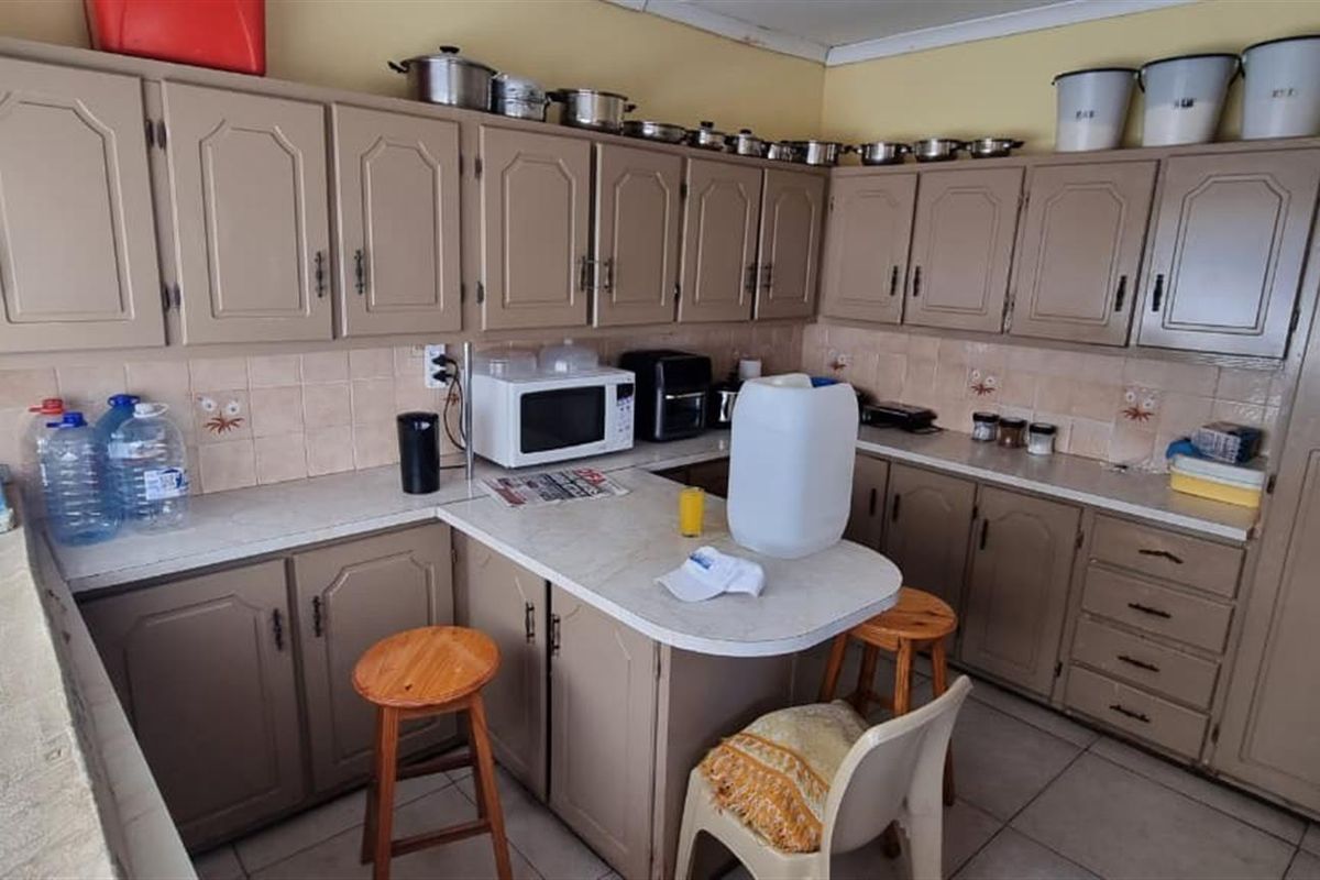 A functional kitchen featuring extensive built-in cabinetry, laminate countertops, and a tiled backsplash, offering a practical layout with ample storage space.