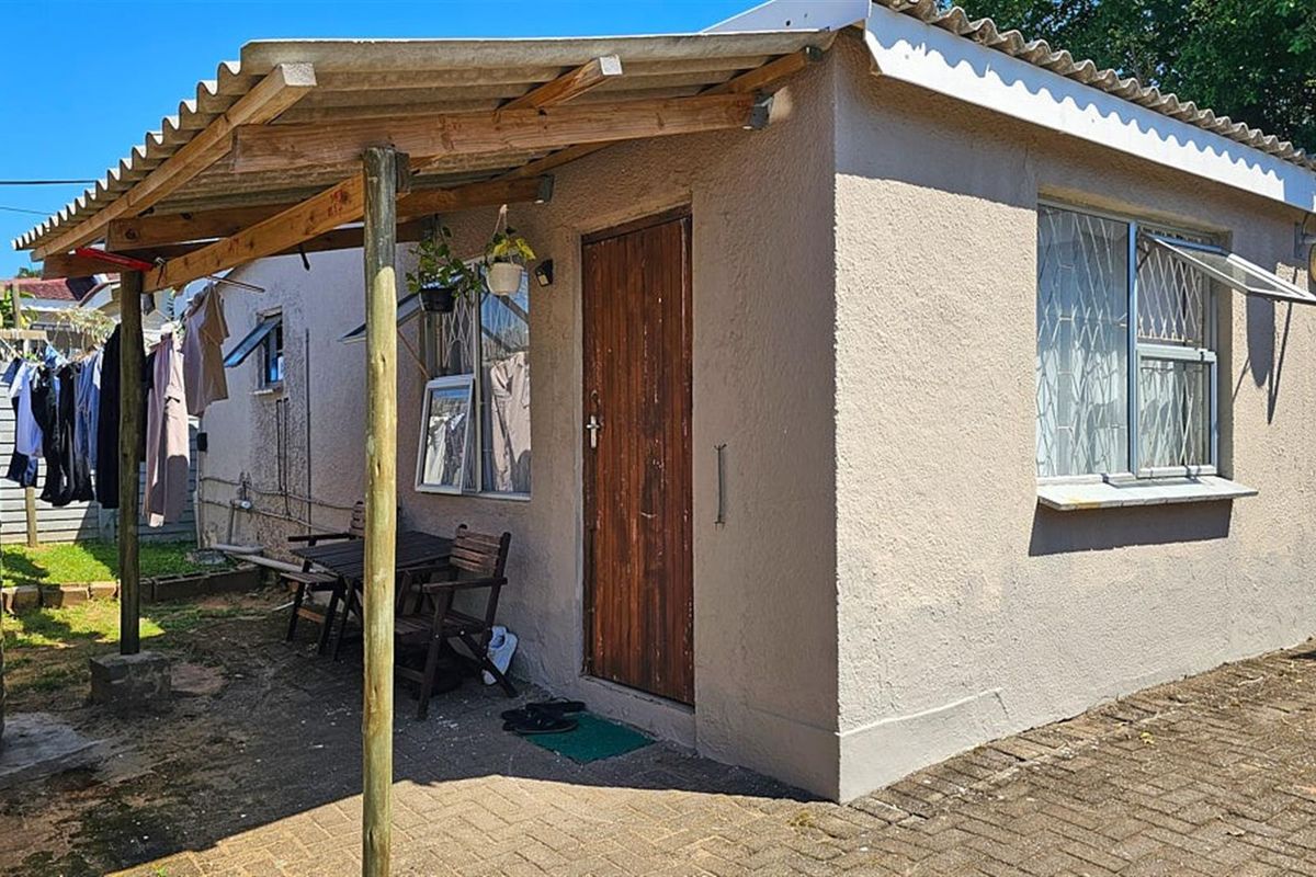 Exterior view of the rear building featuring a covered patio area, timber support posts, and security-barred windows.