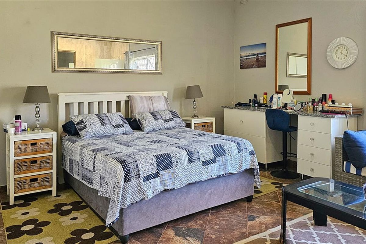A spacious bedroom featuring tiled flooring, a built-in vanity unit with stone countertop, and neutral wall finishes.