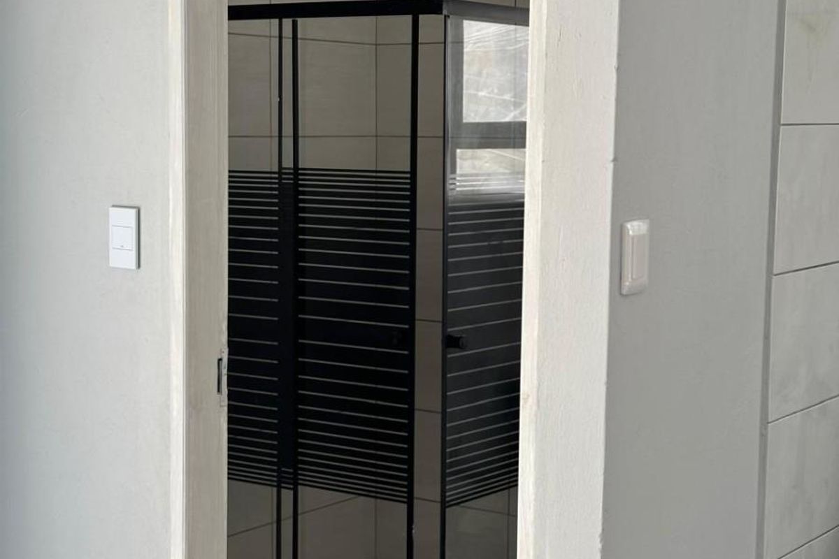 A modern bathroom featuring a walk-in shower with a black-framed enclosure and a contemporary rain shower head.
