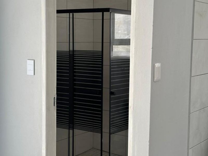 A modern bathroom featuring a walk-in shower with a black-framed enclosure and a contemporary rain shower head.