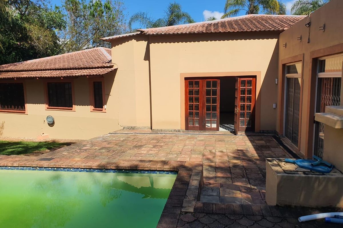 Rear exterior view featuring a swimming pool, terracotta tiled patio, and timber french doors leading into the home.