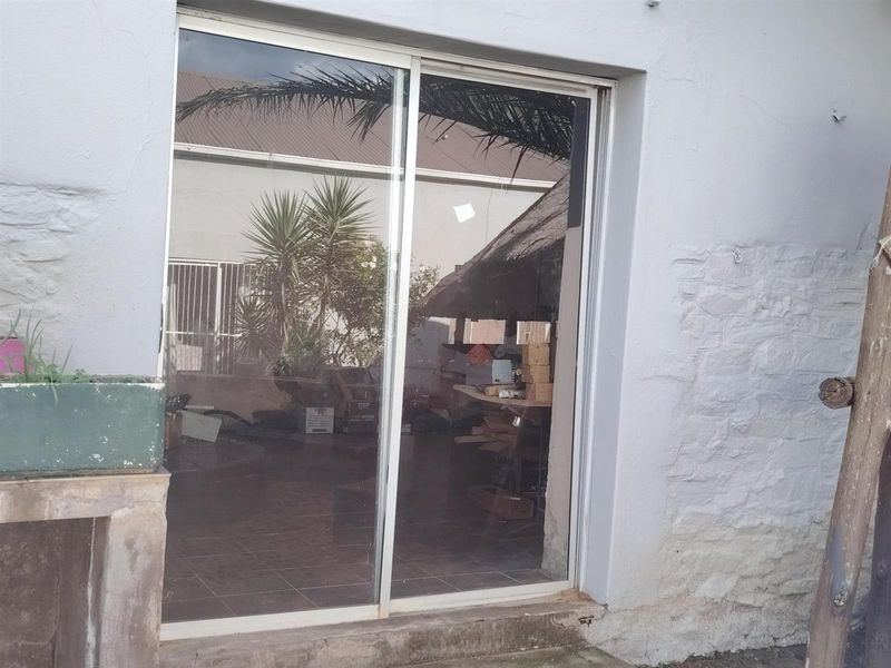 Exterior view of a sliding glass door entrance featuring a textured masonry wall and concrete threshold, providing access to the interior living space.