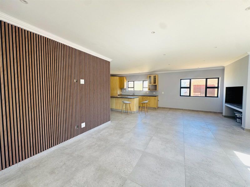 Spacious open-plan living area featuring a modern slatted timber feature wall, large format floor tiles, and a functional kitchen with island cabinetry.