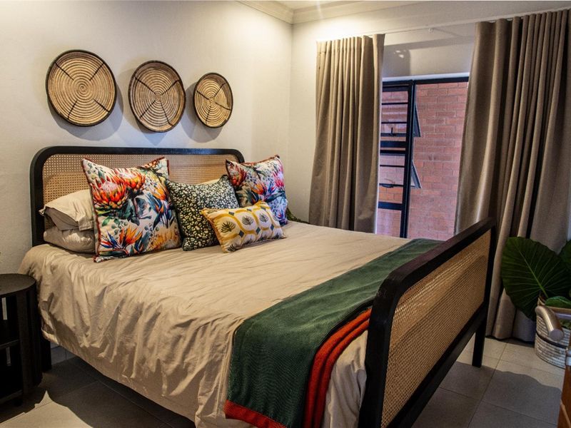 A well-lit bedroom featuring tiled flooring, neutral wall finishes, and a sliding door providing access to an outdoor area.