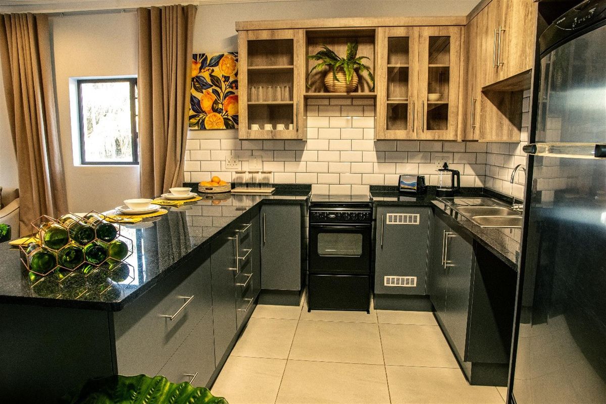 Modern kitchen featuring dark cabinetry, granite countertops, subway tile backsplash, and built-in oven with hob, offering a functional and stylish cooking space.