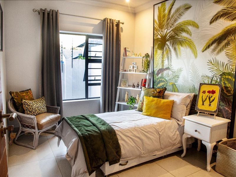 A well-maintained bedroom featuring tiled flooring, large window with curtain rails, and a decorative feature wall.