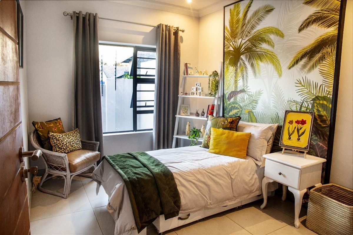 A well-maintained bedroom featuring tiled flooring, large window with curtain rails, and a decorative feature wall.