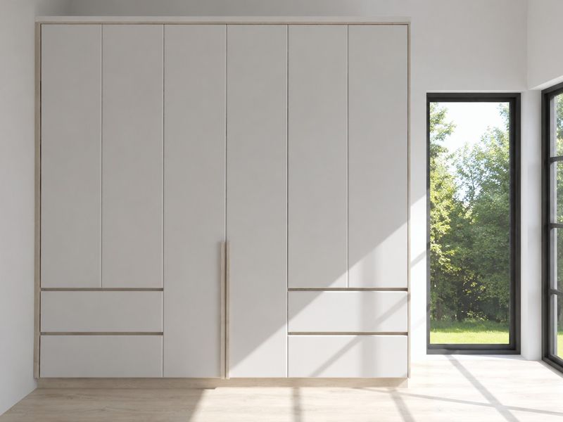A modern bedroom featuring a large, sleek built-in wardrobe with integrated handles and a floor-to-ceiling window overlooking a garden.