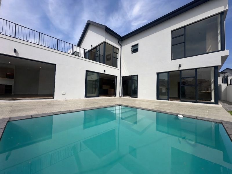 Modern rear exterior featuring a swimming pool, tiled patio area, and large sliding glass doors providing seamless indoor-outdoor flow.