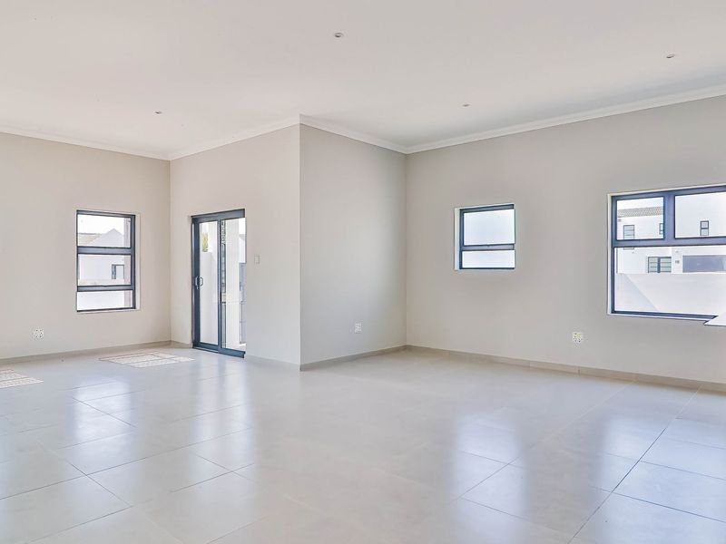 Spacious open-plan living area featuring neutral tiled flooring, modern recessed lighting, and a contemporary kitchen island with slatted timber detailing.
