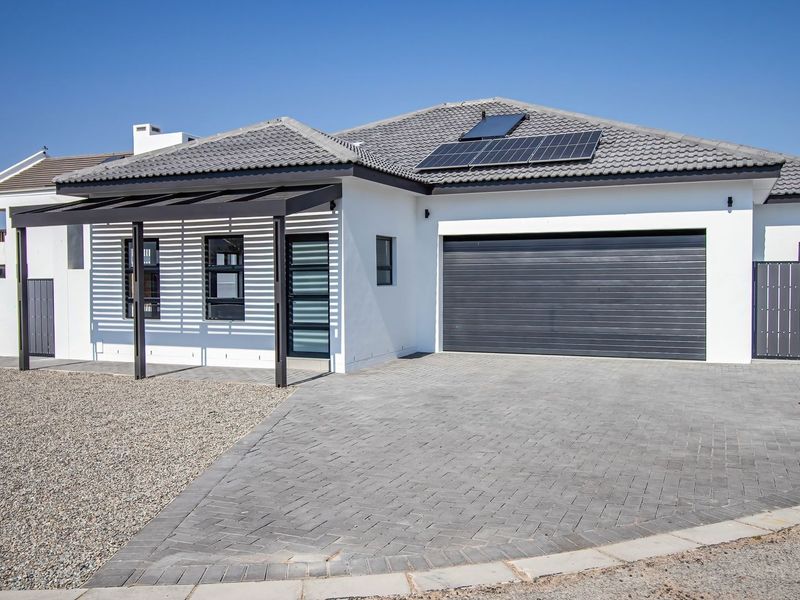Modern single-story home featuring a paved driveway, automated garage, solar energy system, and a covered pergola entrance.