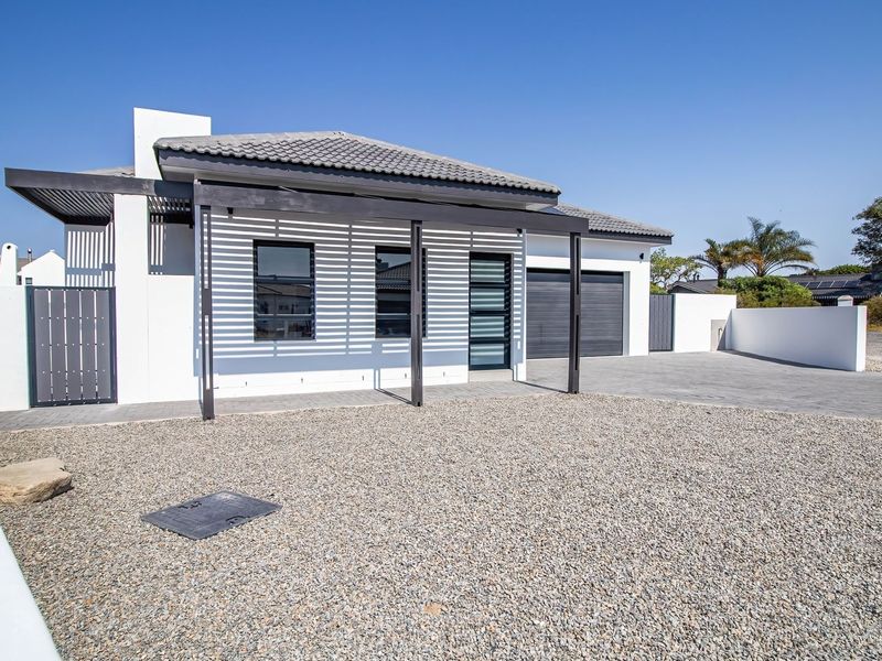 Modern single-story house featuring a tiled roof, paved driveway, double garage, and a stylish pergola over the entrance area.