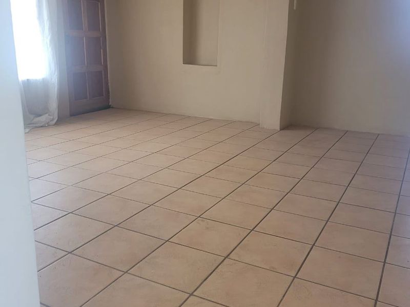 An empty living room featuring neutral wall paint, tiled flooring, and a built-in recessed wall niche.