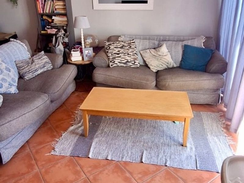 A living room featuring terracotta floor tiles, a ceiling fan, and access to a balcony through a sliding glass door.