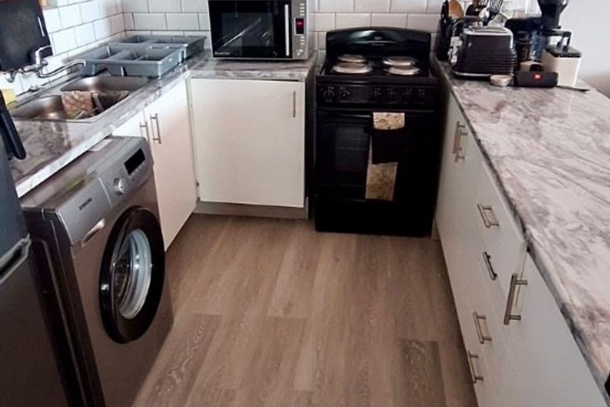 A functional kitchen featuring white cabinetry, subway tile backsplash, marble-look countertops, and modern vinyl plank flooring.
