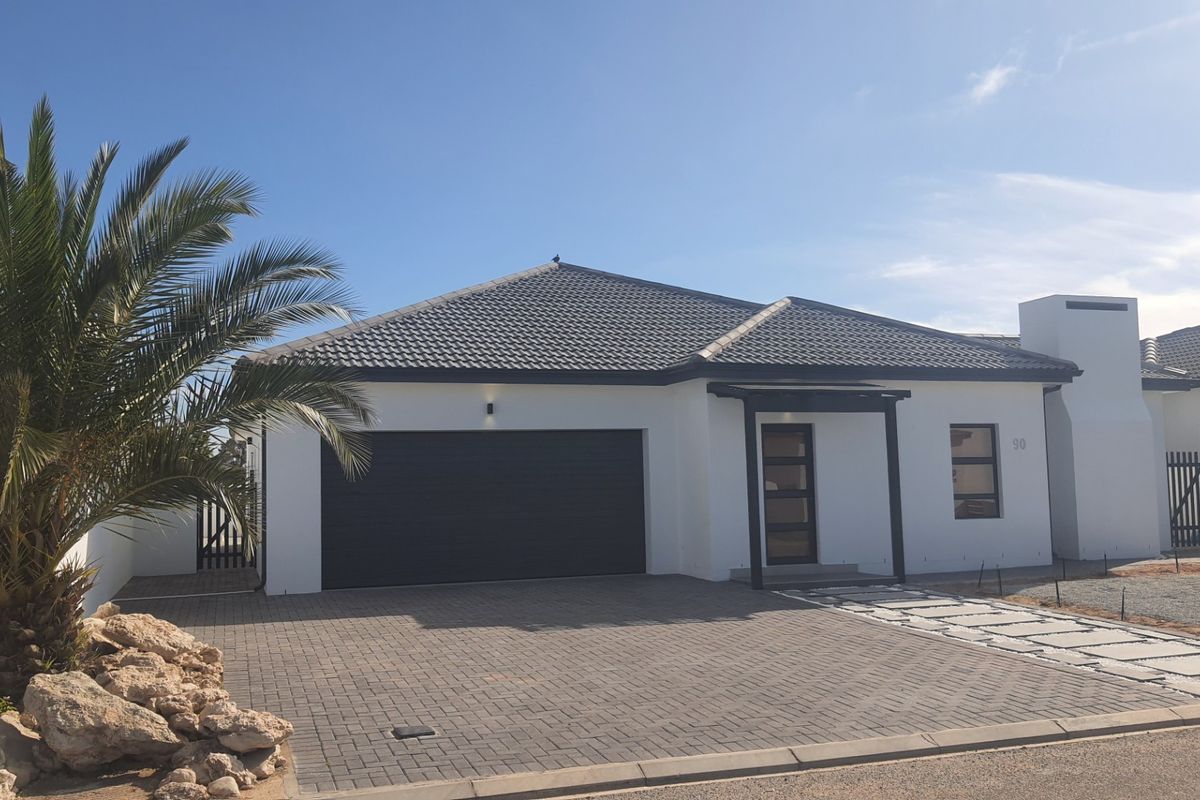 Modern single-story home featuring a tiled roof, double garage, paved driveway, and clean white facade with contemporary architectural details.