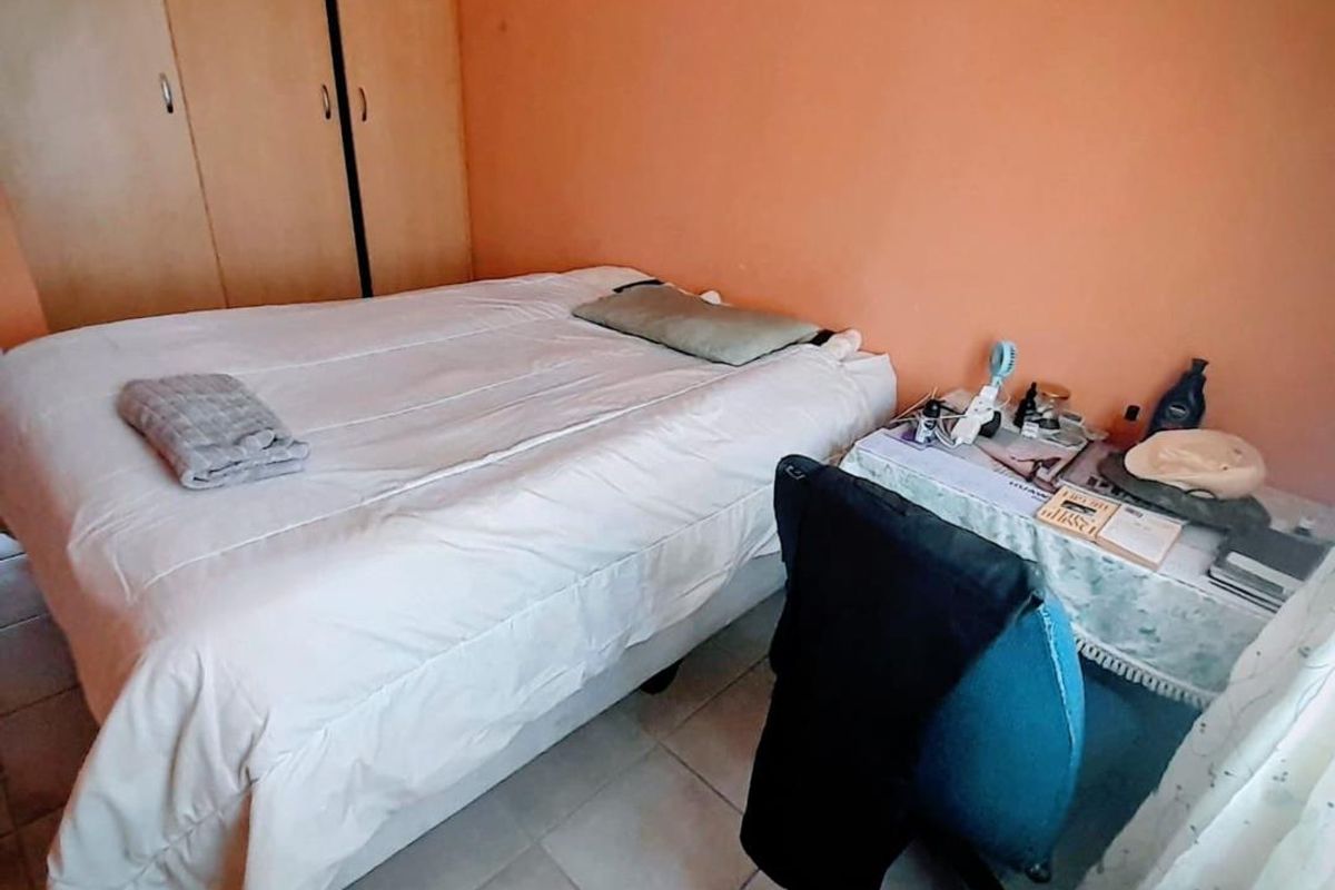 A bedroom featuring built-in wooden cupboards and tiled flooring, offering a functional space with potential for cosmetic updates.