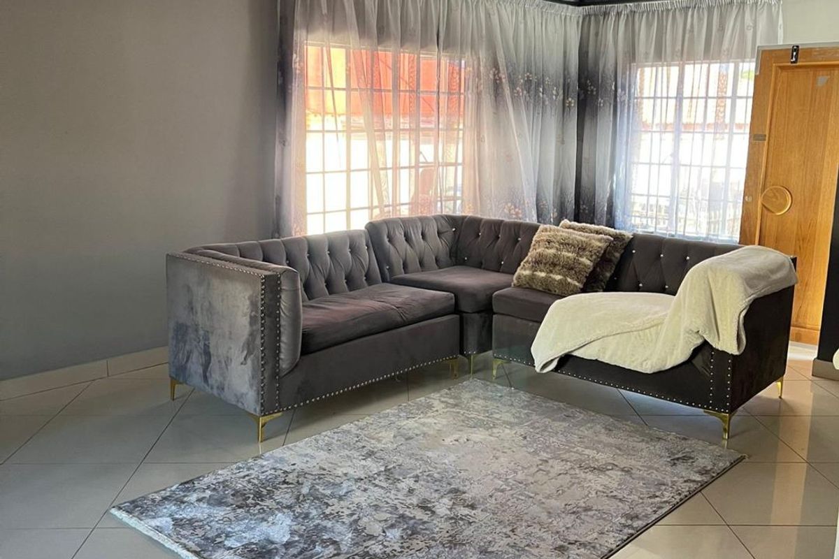 A living room featuring large format floor tiles, a decorative ceiling with recessed lighting, and a crystal chandelier.