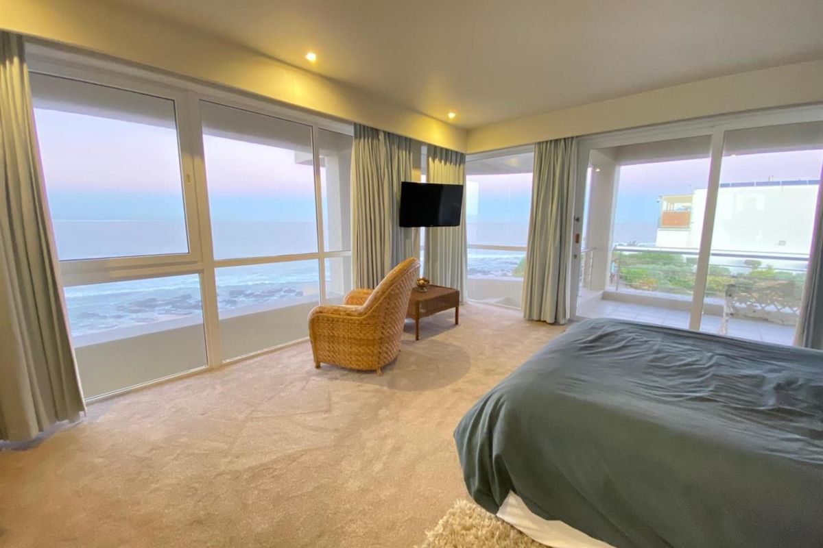 Spacious bedroom featuring expansive floor-to-ceiling windows with panoramic ocean views and direct access to a private balcony.