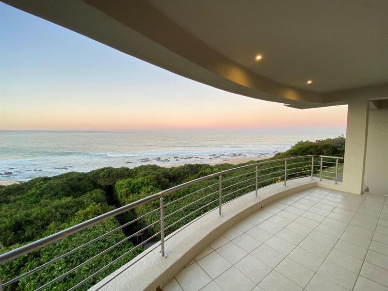 Spacious covered balcony featuring a stainless steel balustrade and tiled flooring, offering panoramic ocean views.
