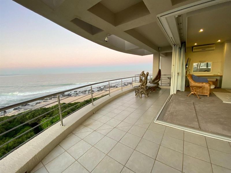 Spacious covered balcony featuring tiled flooring, stainless steel balustrades, and direct access to the interior living area with panoramic ocean views.