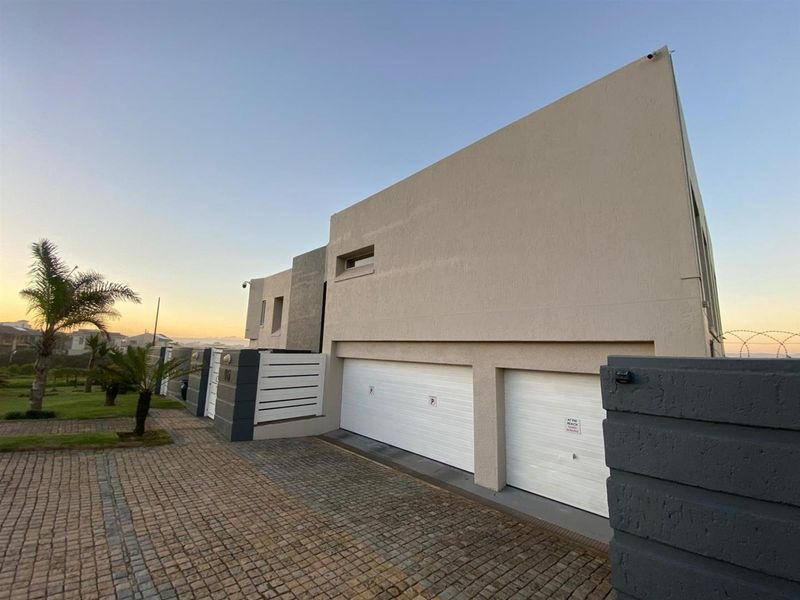 Modern exterior view of the property featuring a double garage, paved driveway, and secure boundary walling.