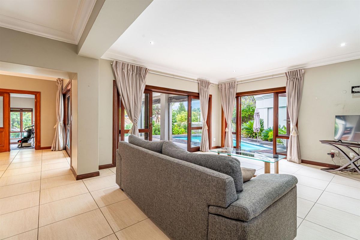 Spacious living area featuring large sliding glass doors that open onto a private swimming pool and patio area.