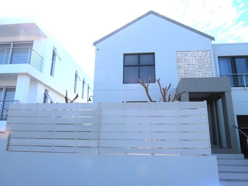 Modern exterior front facade featuring clean lines, stone cladding accents, and a contemporary horizontal slat privacy fence.