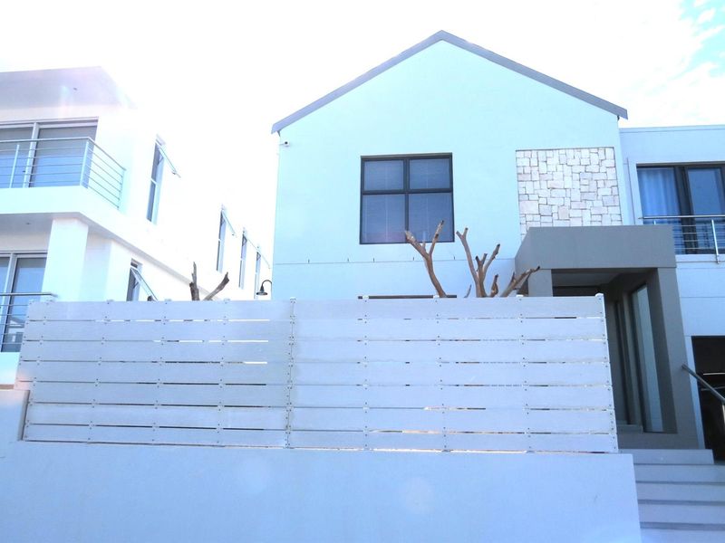 Modern exterior front elevation featuring a clean facade, stone cladding accents, horizontal privacy fencing, and a contemporary architectural design.
