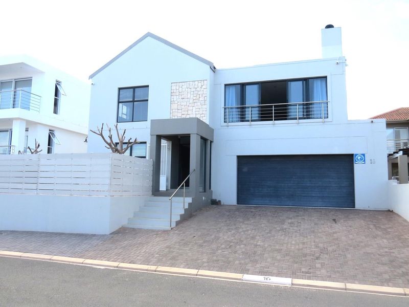 Modern double-story residence featuring a paved driveway, integrated garage, stone-clad accent wall, and a balcony with stainless steel railings.