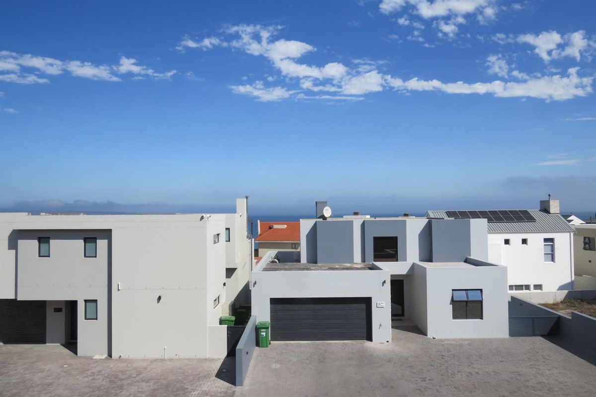 An elevated view of a modern two-story residential property featuring a paved driveway, integrated garage, and contemporary grey facade.