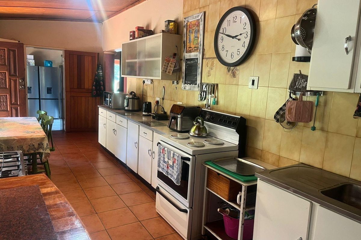 A functional kitchen featuring tiled flooring, built-in cabinetry, and a freestanding stove, with an adjacent dining area and access to a secondary room.