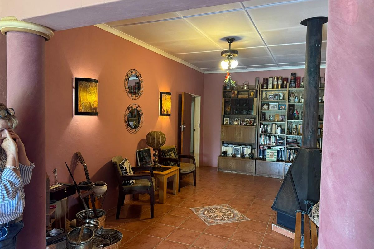 A living room featuring terracotta floor tiles, a built-in fireplace, and decorative wall sconces, creating a warm and traditional atmosphere.