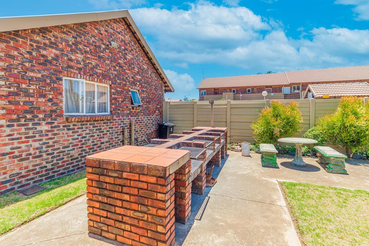 A private rear courtyard featuring a built-in brick braai area, concrete paving, and perimeter walling, providing a functional outdoor entertainment space.