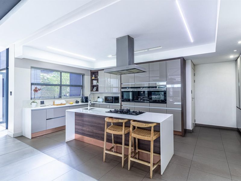 Modern kitchen featuring a central island with gas cooktop, integrated appliances, sleek cabinetry, and high-quality stone countertops in a bright, open-plan layout.