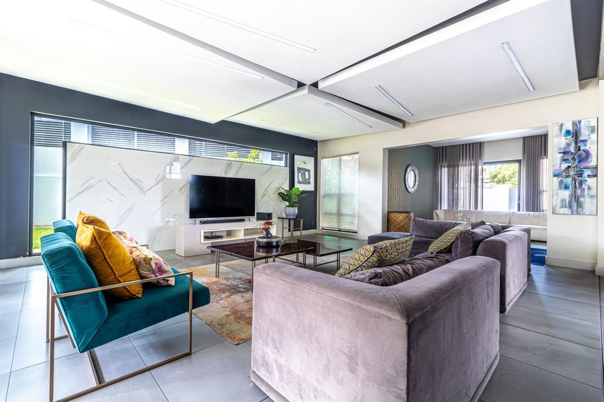 Spacious modern living room featuring a marble-look feature wall, recessed ceiling with integrated lighting, and large format floor tiles.