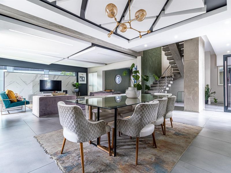 Spacious open-plan living and dining area featuring a modern concrete staircase, marble feature wall, and sophisticated coffered ceiling design.