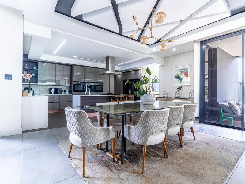 Modern open-plan living and dining area featuring a sleek kitchen with integrated appliances, high-end finishes, and seamless access to the outdoor patio.