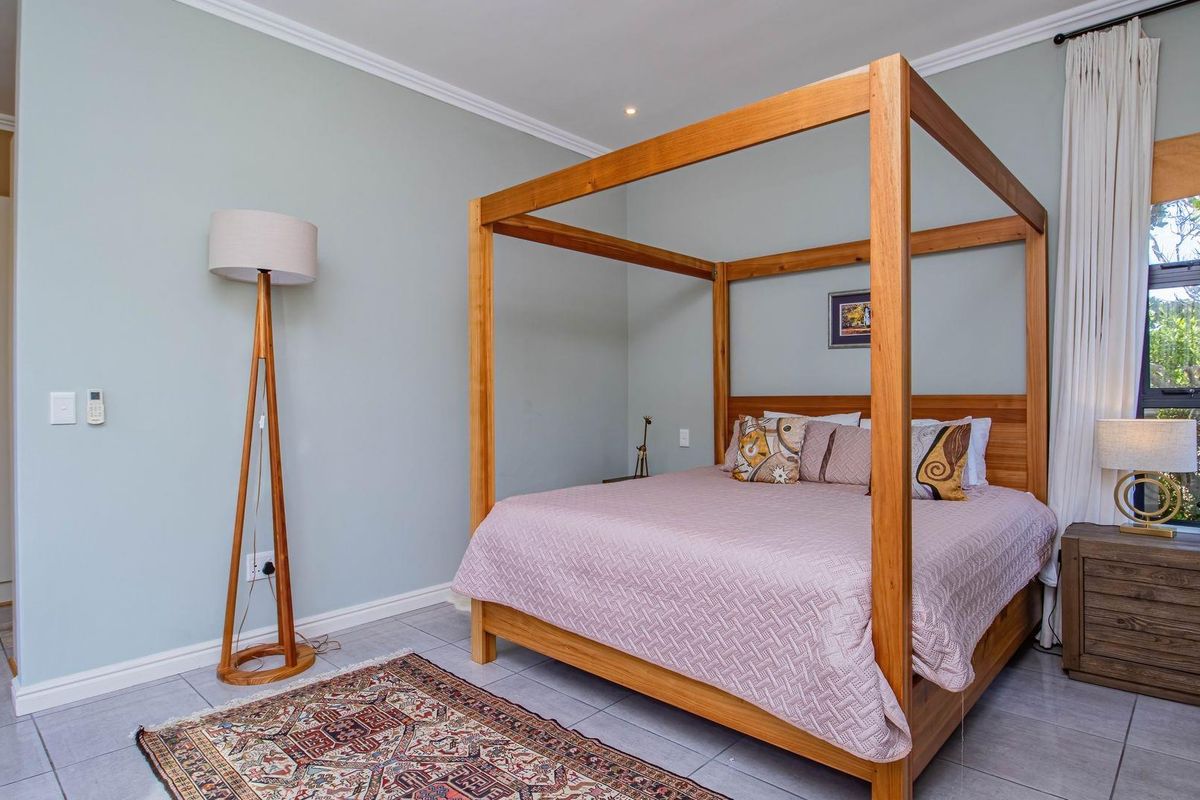A well-maintained bedroom featuring tiled flooring, crown molding, and a large window allowing natural light into the space.