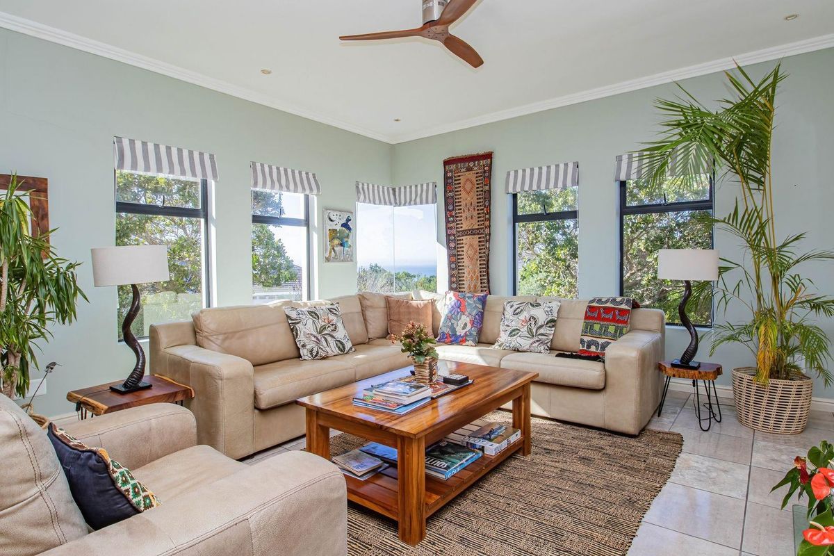A bright and airy living room featuring large windows with views, tiled flooring, and a ceiling fan.