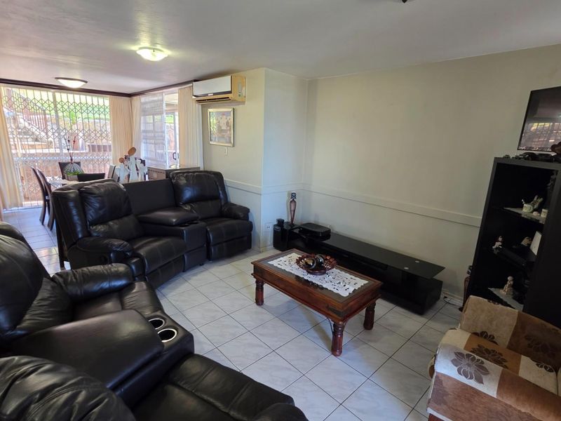 Open plan living area featuring tiled flooring, wall-mounted air conditioning unit, and direct access to an outdoor patio space.