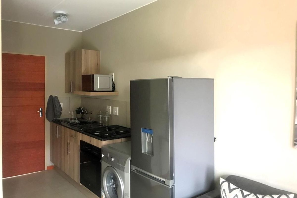 Compact kitchenette featuring built-in cabinetry, a dark countertop, integrated stove and oven, and space for a washing machine.