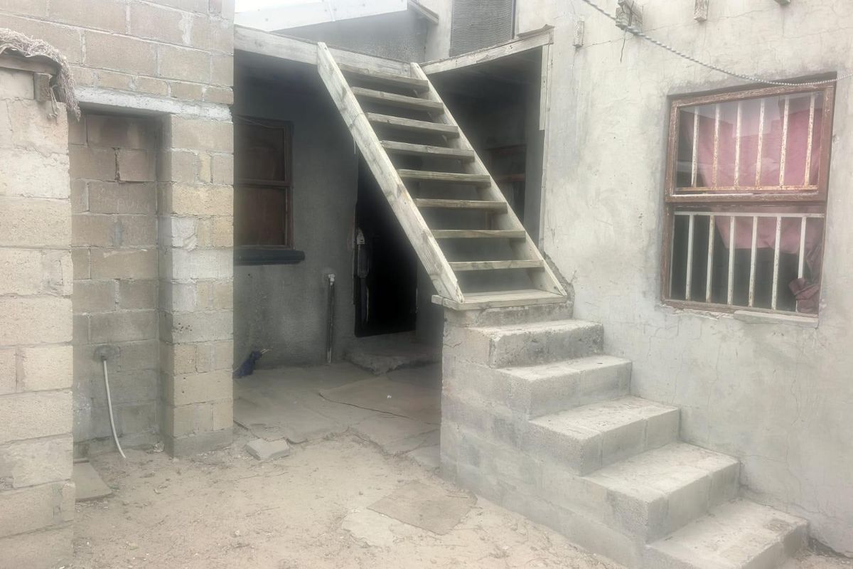 Rear exterior view of a property featuring unfinished concrete block walls and an external staircase leading to an upper level.