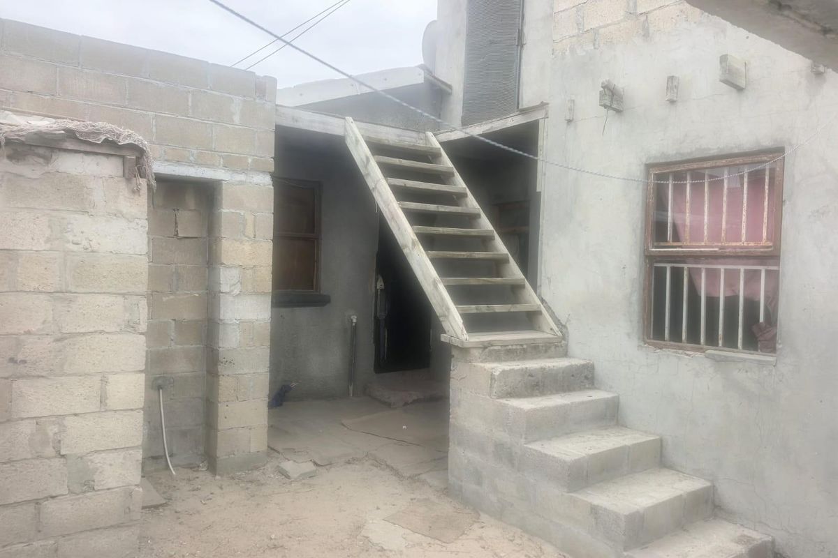 Rear exterior view of a property featuring unfinished concrete block walls and an external staircase leading to an upper level.